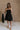 Full body view of female model wearing the Abigail Strapless Flare Mini Dress in black which features features Mini Length, Lining, Two Side Pockets, Strapless and Monochrome Back Zipper with Hook Closure.
