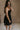 Side view of female model wearing the Abigail Strapless Flare Mini Dress in black which features features Mini Length, Lining, Two Side Pockets, Strapless and Monochrome Back Zipper with Hook Closure.