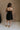 Full body back view of female model wearing the Abigail Strapless Flare Mini Dress in black which features features Mini Length, Lining, Two Side Pockets, Strapless and Monochrome Back Zipper with Hook Closure.