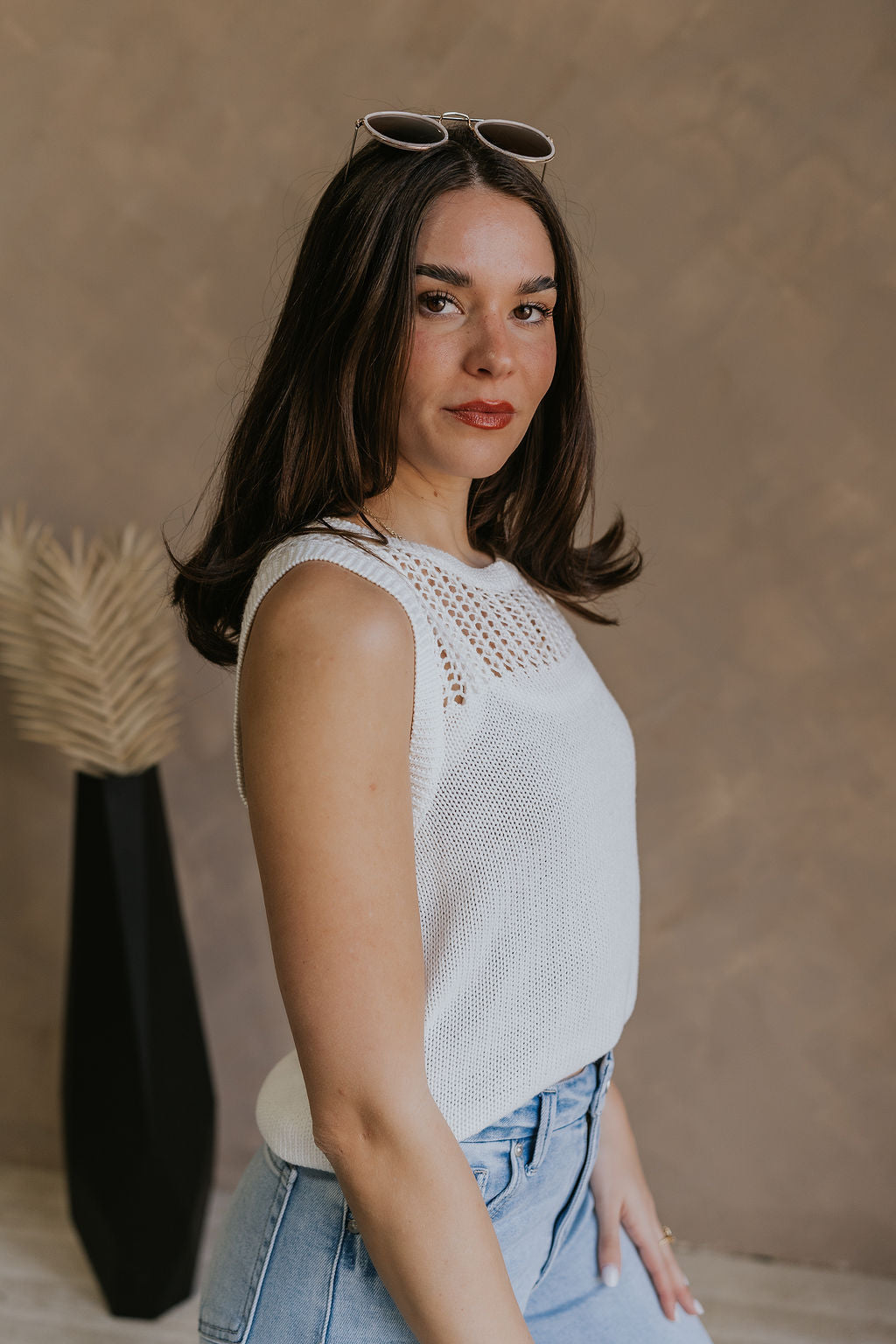Side view of female model wearing the Elisa Cream Knit Sleeveless Tank which features Cream Cotton Fabric, Open Knit Details, Round Neckline and Sleeveless
