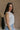 Side view of female model wearing the Elisa Cream Knit Sleeveless Tank which features Cream Cotton Fabric, Open Knit Details, Round Neckline and Sleeveless