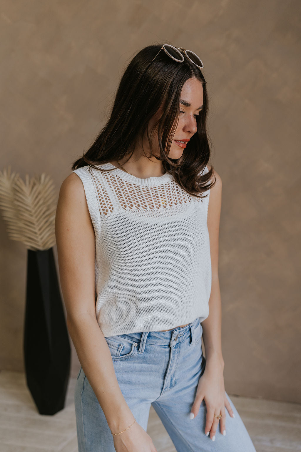 Side view of female model wearing the Elisa Cream Knit Sleeveless Tank which features Cream Cotton Fabric, Open Knit Details, Round Neckline and Sleeveless