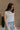 Side view of female model wearing the Elisa Cream Knit Sleeveless Tank which features Cream Cotton Fabric, Open Knit Details, Round Neckline and Sleeveless