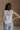 Back view of female model wearing the Elisa Cream Knit Sleeveless Tank which features Cream Cotton Fabric, Open Knit Details, Round Neckline and Sleeveless