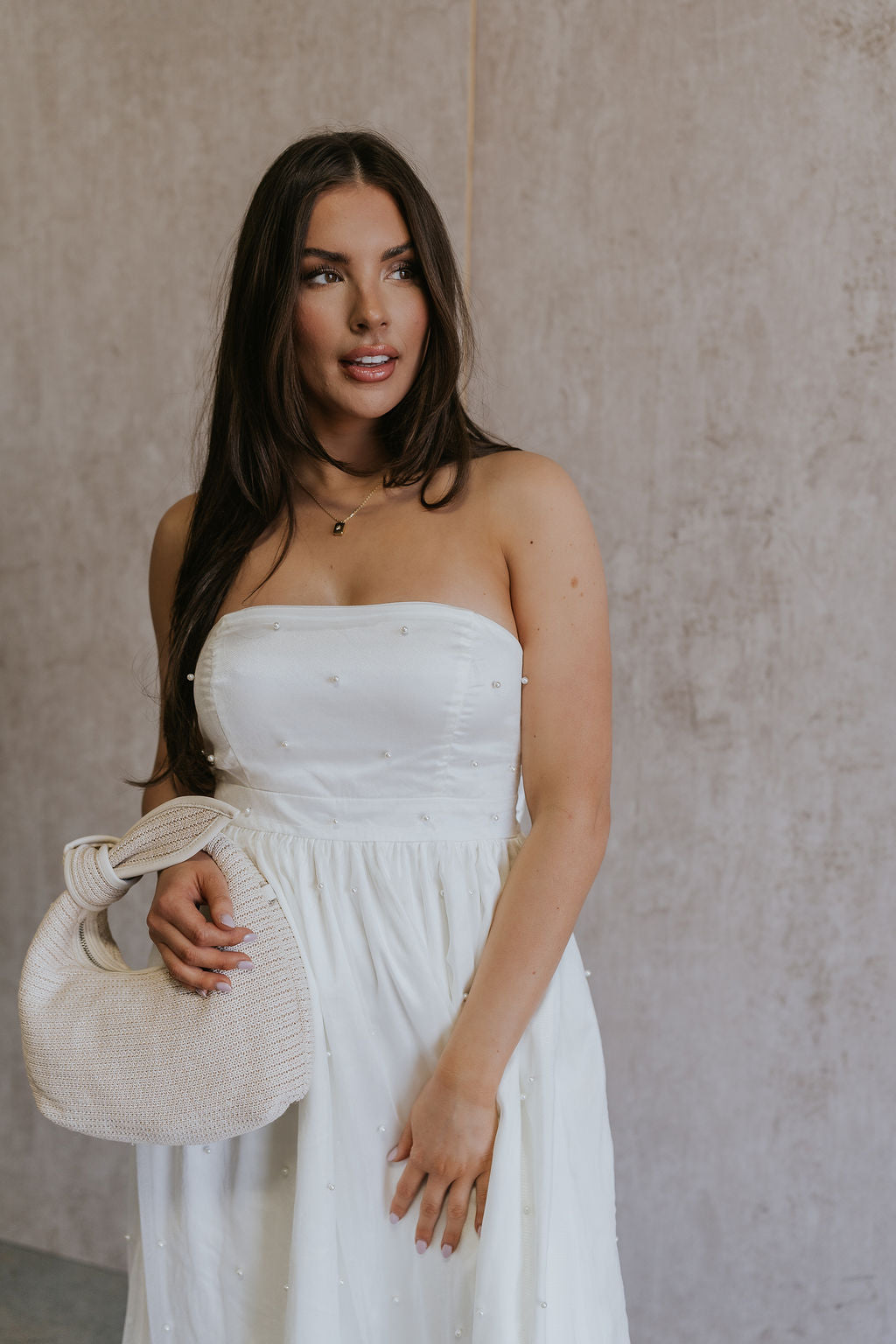 Front view of female model wearing the Rebecca Off White Pearl Bow Midi Dress which featuresCream Sheer Fabric, Midi Length, Cream Lining, Strapless, Pearl Details and Bow Back Detail