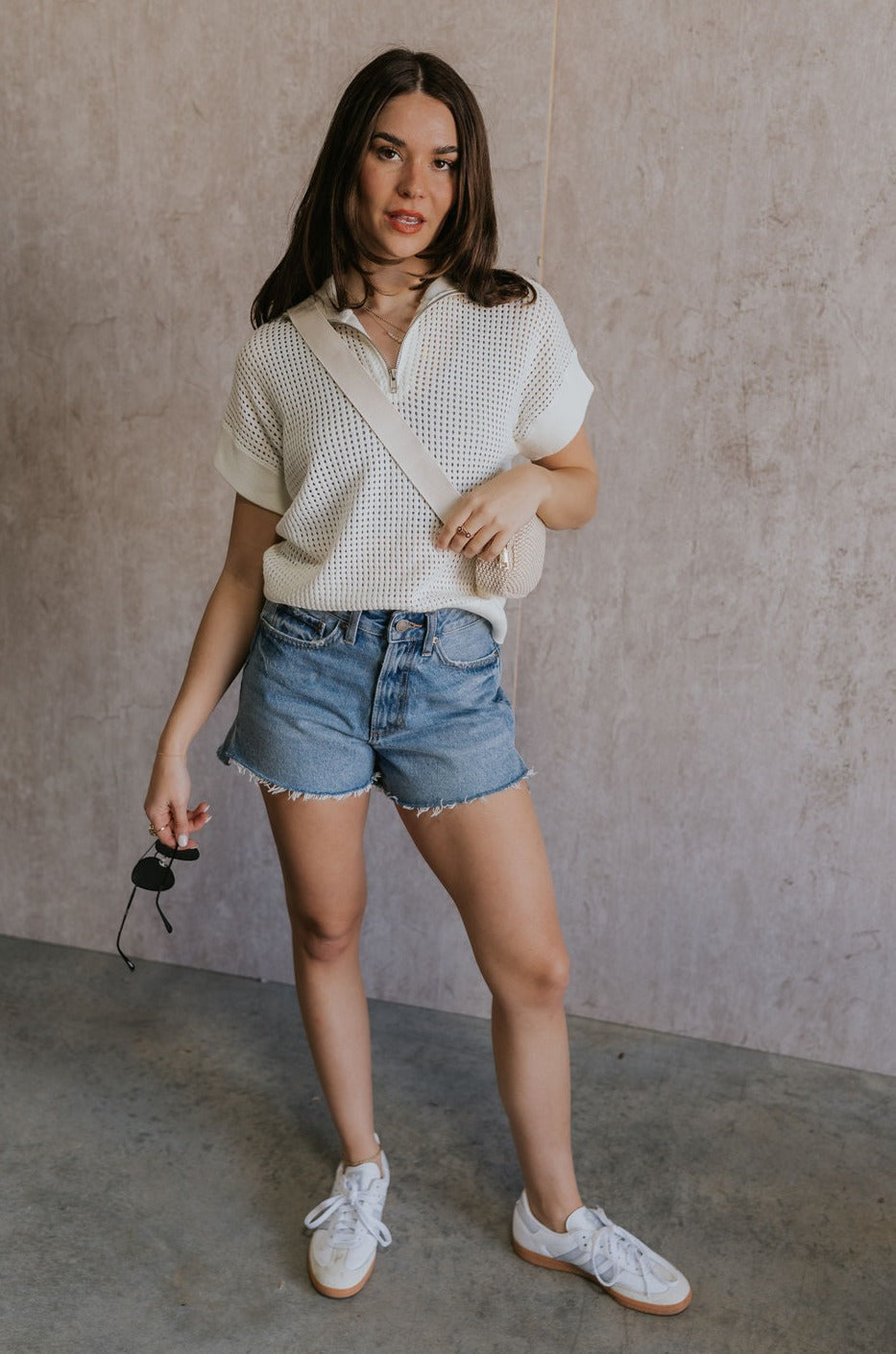 Full body view of female model wearing the Julia White Knit Short Sleeve Top which features Cream Open Knit Fabric, Ribbed Hem, Short Sleeves and Quarter Zip-Up 