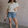 Full body view of female model wearing the Julia White Knit Short Sleeve Top which features Cream Open Knit Fabric, Ribbed Hem, Short Sleeves and Quarter Zip-Up 