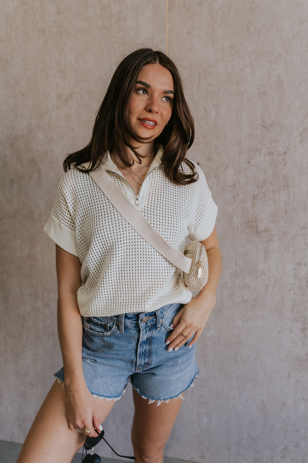 Front view of female model wearing the Julia White Knit Short Sleeve Top which features Cream Open Knit Fabric, Ribbed Hem, Short Sleeves and Quarter Zip-Up