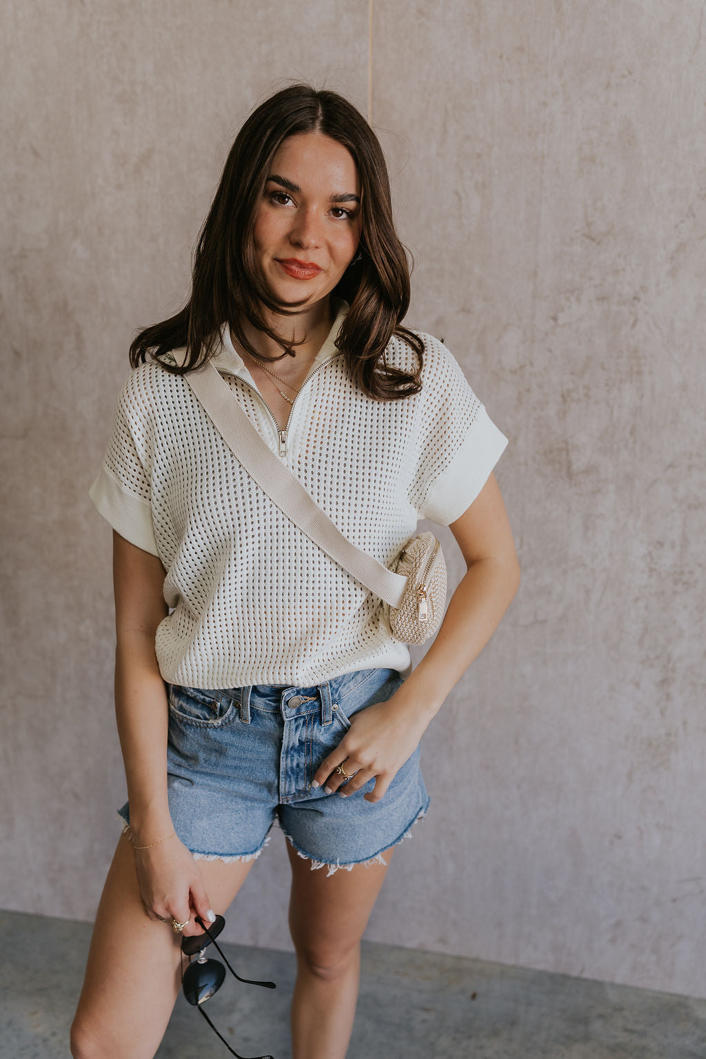 Front view of female model wearing the Julia White Knit Short Sleeve Top which features Cream Open Knit Fabric, Ribbed Hem, Short Sleeves and Quarter Zip-Up