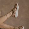 Right side view of female model wearing the Fighter Sandal in Natural which features natural tan texture fabric, rattan details, white platform sole and adjustable velcro straps