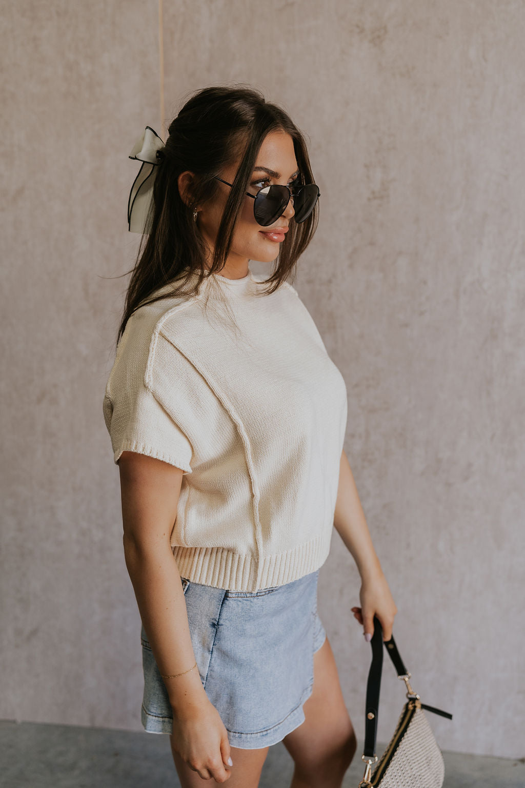 Side view of model wearing the Emma Cream Knit Short Sleeve Top which features Cream Knit Fabric, Ribbed Hem, Round Neckline and Short Sleeves.