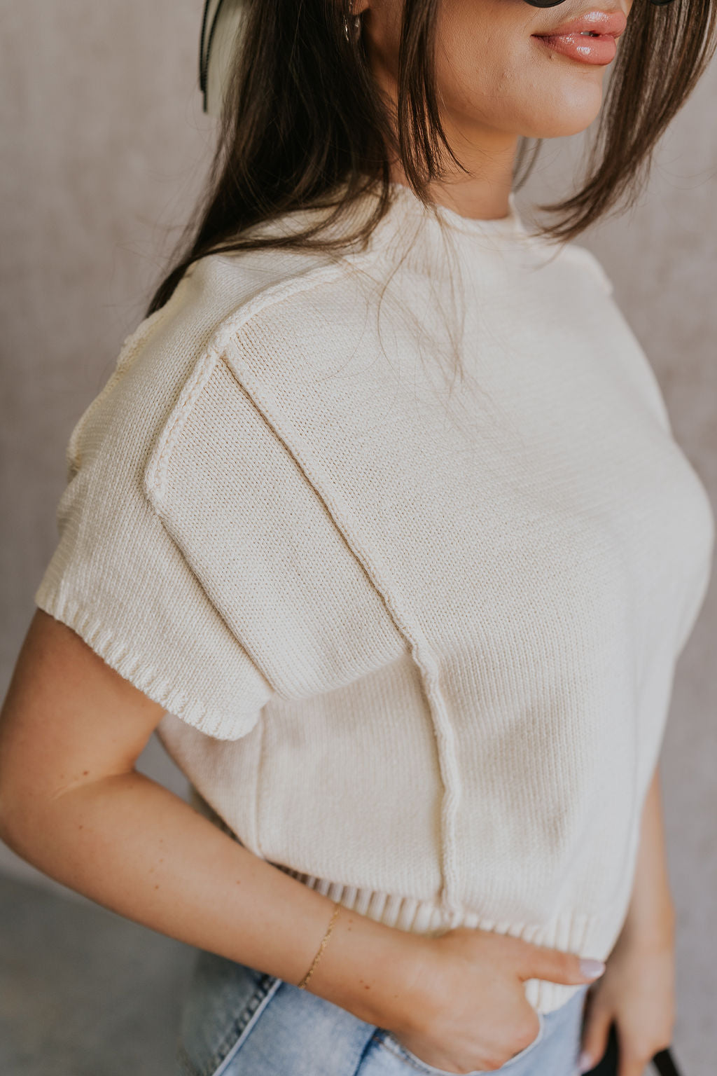 Close up side view of model wearing the Emma Cream Knit Short Sleeve Top which features Cream Knit Fabric, Ribbed Hem, Round Neckline and Short Sleeves.