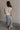 Full body back view of female model wearing the Vivian Ivory & Navy Knit Sleeveless Sweater which features Cream Cable Knit Fabric, Navy Trim Details, Left Front Chest Pocket, High Neckline and Sleeveless.