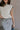 Close up  view of female model wearing the Vivian Ivory & Navy Knit Sleeveless Sweater which features Cream Cable Knit Fabric, Navy Trim Details, Left Front Chest Pocket, High Neckline and Sleeveless.