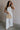 Full body view of female model wearing the Sienna Off White & Tan Sleeveless Tank which features White Ribbed Fabric, Tan Trim Details, Round Neckline and Sleeveless
