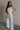 Full body view of female model wearing the Sienna Off White & Tan Sleeveless Tank which features White Ribbed Fabric, Tan Trim Details, Round Neckline and Sleeveless