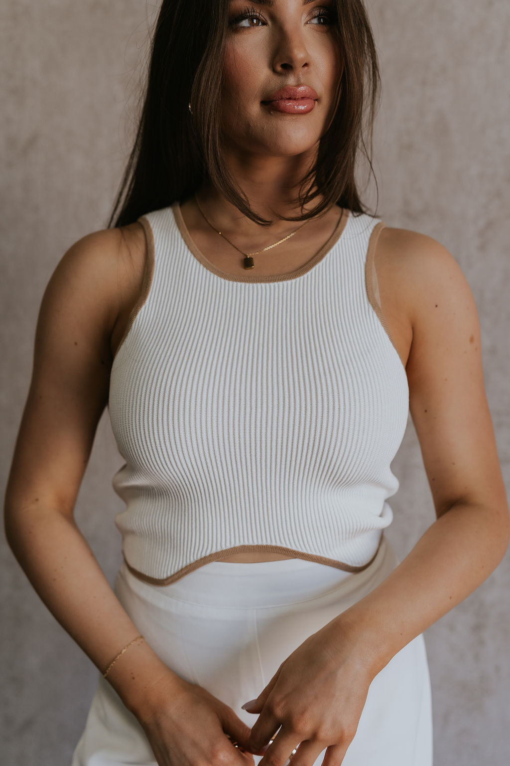Close up front view of female model wearing the Sienna Off White & Tan Sleeveless Tank which features White Ribbed Fabric, Tan Trim Details, Round Neckline and Sleeveless