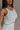 Close up side view of female model wearing the Sienna Off White & Tan Sleeveless Tank which features White Ribbed Fabric, Tan Trim Details, Round Neckline and Sleeveless