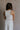 Back view of female model wearing the Sienna Off White & Tan Sleeveless Tank which features White Ribbed Fabric, Tan Trim Details, Round Neckline and Sleeveless
