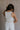 Back view of female model wearing the Sienna Off White & Tan Sleeveless Tank which features White Ribbed Fabric, Tan Trim Details, Round Neckline and Sleeveless