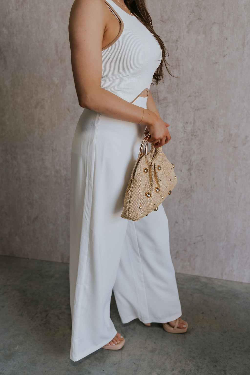 Side view of female model wearing the Sloane White Wide Leg Pants which features White Lightweight Fabric, Wide Leg Pants, Side Zipper with Hook Closure and White Lining
