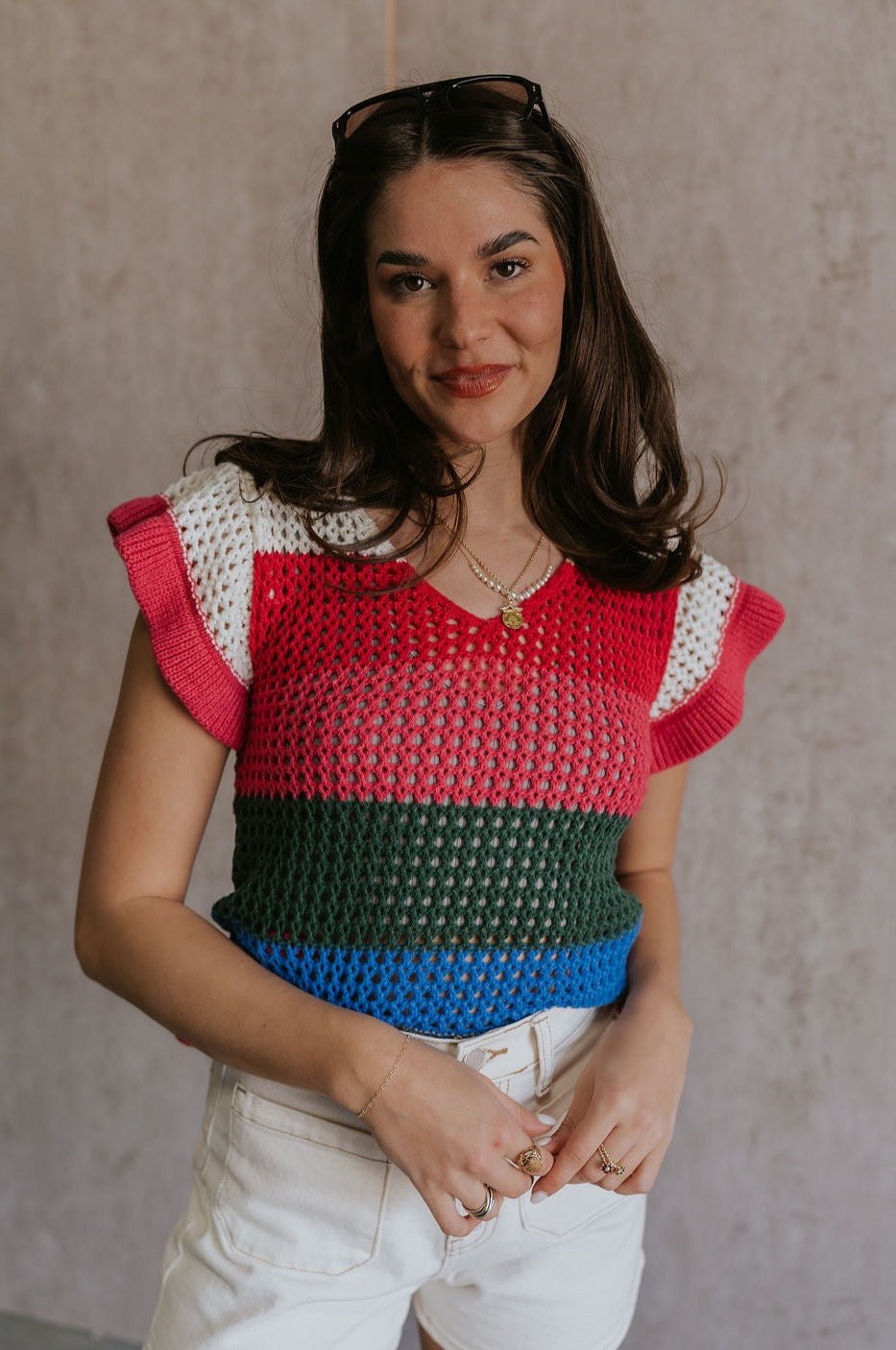 Front view of female model wearing the Andrea Pink Multi Knit Ruffle Top which features Blue, Green, Pink, Grey and Cream Open Knit Fabric, Ruffle Hem, V-Neckline and Short Sleeves