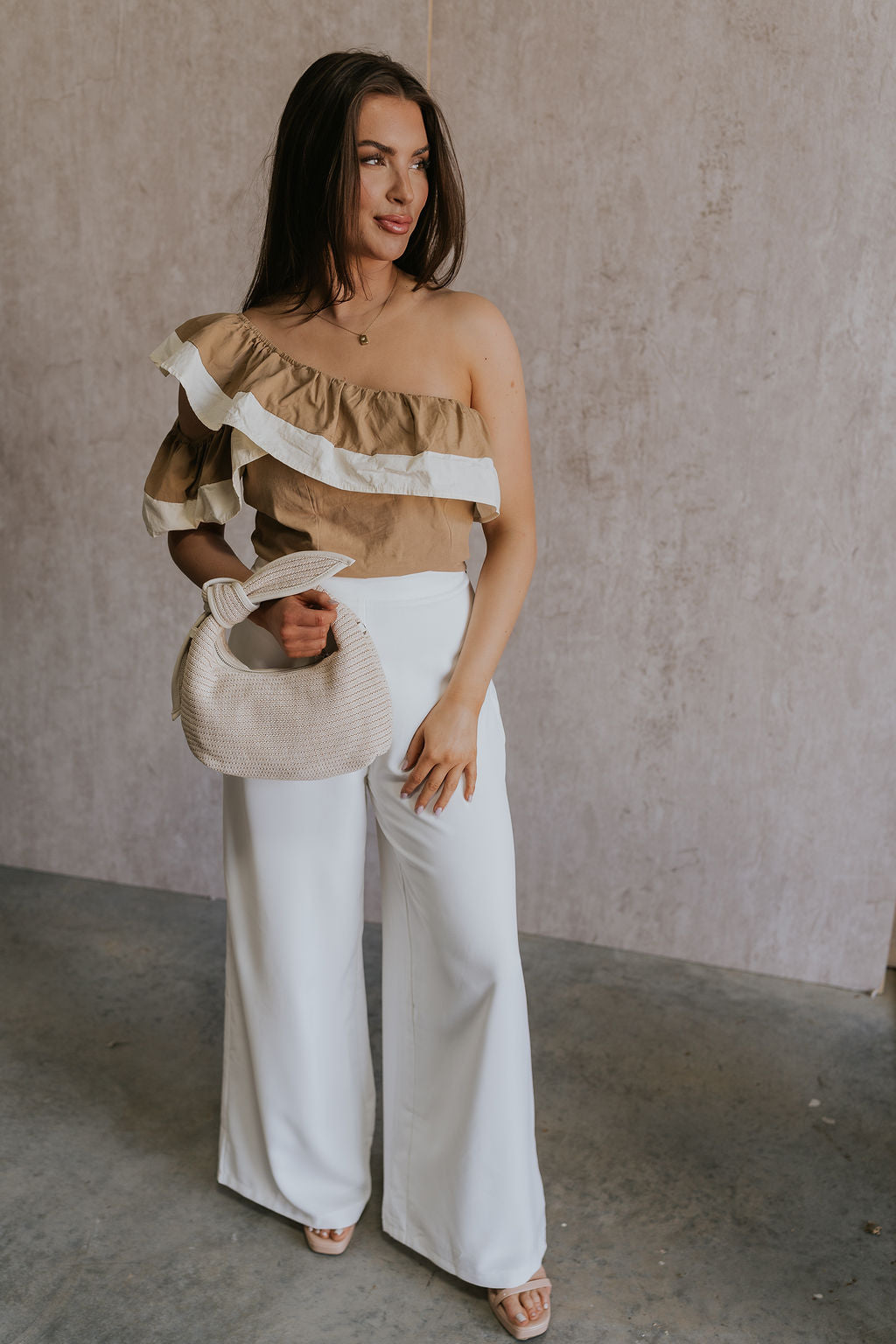 Full body view of female model wearing the Rosalie Khaki & Cream Ruffle One-Shoulder Top which features Brown and Cream Lightweight Fabric, Cropped Waist, Side Zipper with Hook Closure, One-Shoulder Ruffle Strap and Sleeveless 