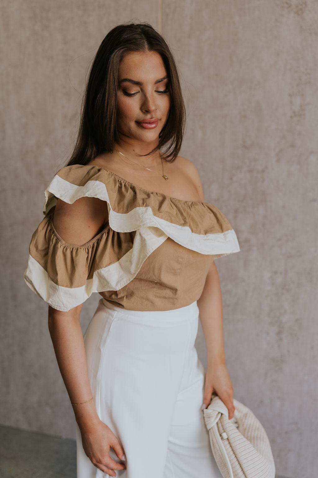 Side view of female model wearing the Rosalie Khaki & Cream Ruffle One-Shoulder Top which features Brown and Cream Lightweight Fabric, Cropped Waist, Side Zipper with Hook Closure, One-Shoulder Ruffle Strap and Sleeveless