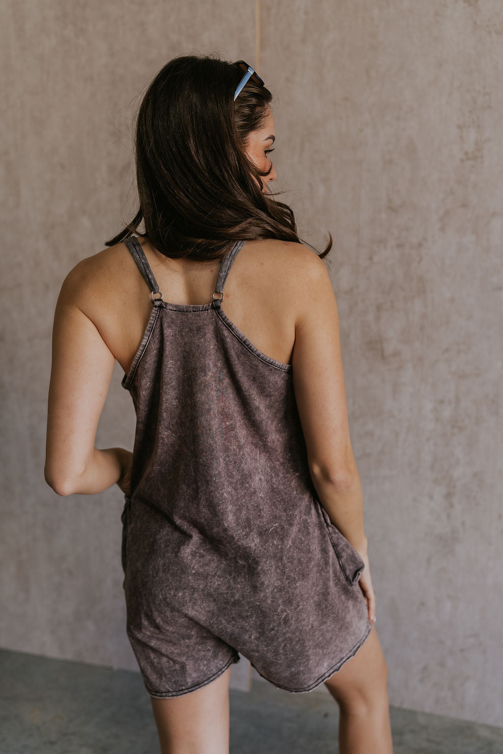 Back view of female model wearing the Vera Washed Black Sleeveless Romper which features Washed Black Cotton Fabric, Two Side Pockets , V-Neckline, Sleeveless and Adjustable Straps