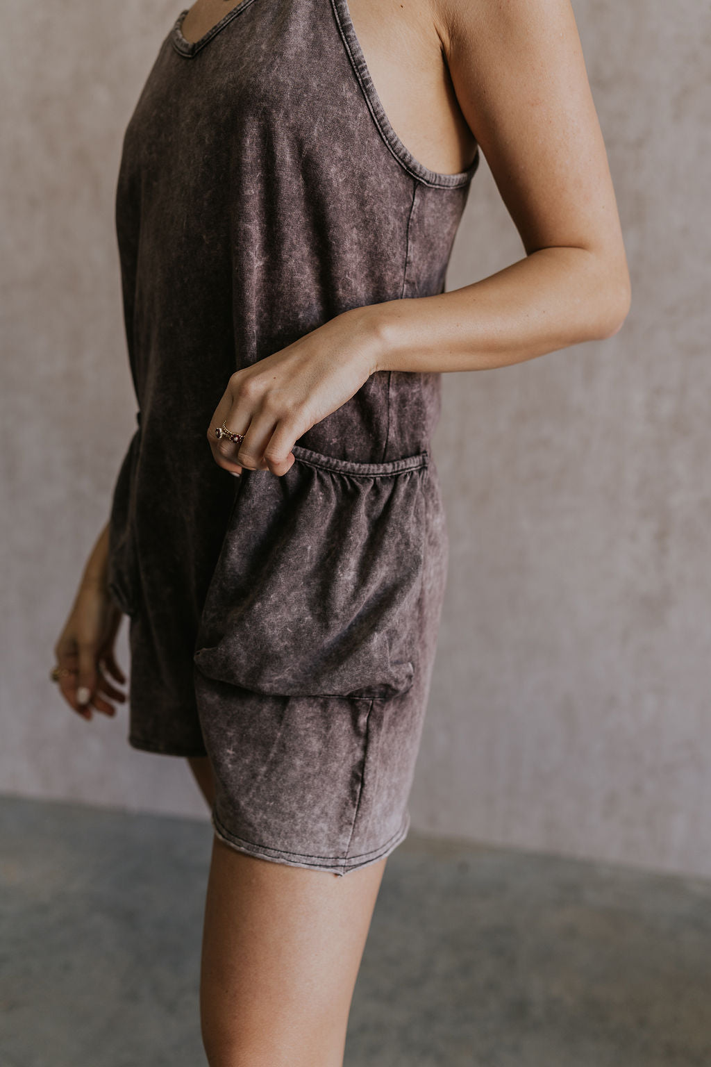 Close up side view of female model wearing the Vera Washed Black Sleeveless Romper which features Washed Black Cotton Fabric, Two Side Pockets , V-Neckline, Sleeveless and Adjustable Straps