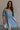 Front view of female model wearing the Hallie Light Chambray Mini Dress which features Light Chambray Tencel Fabric, Mini Length, Square Neckline, Half Sleeves with Ruffle Hem Details and Smocked Back