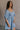 Side view of female model wearing the Hallie Light Chambray Mini Dress which features Light Chambray Tencel Fabric, Mini Length, Square Neckline, Half Sleeves with Ruffle Hem Details and Smocked Back