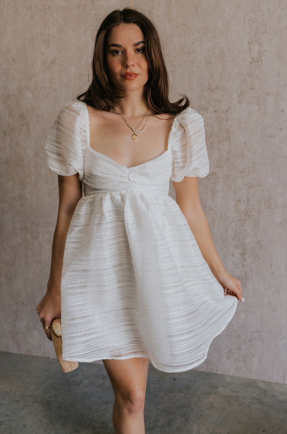 Front view of female model wearing the Julia Off White Short Puff Sleeve Mini Dress which features Off White Stripe Sheer Fabric, White Lining, Mini Length, Ruched Upper, Sweetheart Neckline, Short Puff Sleeves and Back Cut-Out Detail with Zipper and Tie Closure