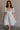 Front view of female model wearing the Julia Off White Short Puff Sleeve Mini Dress which features Off White Stripe Sheer Fabric, White Lining, Mini Length, Ruched Upper, Sweetheart Neckline, Short Puff Sleeves and Back Cut-Out Detail with Zipper and Tie Closure