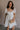 Front view of female model wearing the Julia Off White Short Puff Sleeve Mini Dress which features Off White Stripe Sheer Fabric, White Lining, Mini Length, Ruched Upper, Sweetheart Neckline, Short Puff Sleeves and Back Cut-Out Detail with Zipper and Tie Closure