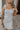 Close up view of female model wearing the Emerson White Blue Floral Ruffle Mini Dress which features White Lightweight Fabric, Blue Floral Print, Ruffle Hem Design, Square Neckline and sleeveless