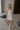 Full body view of female model wearing the Emerson White Blue Floral Ruffle Mini Dress which features White Lightweight Fabric, Blue Floral Print, Ruffle Hem Design, Square Neckline and sleeveless