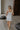 Full body back view of female model wearing the Emerson White Blue Floral Ruffle Mini Dress which features White Lightweight Fabric, Blue Floral Print, Ruffle Hem Design, Square Neckline and sleeveless