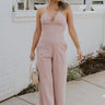 Full body view of female model wearing the Aleah Mauve Pink Sleeveless Jumpsuit which features Mauve Pink Lightweight Fabric, Wide Leg Pants, Upper Ruched Detail, Two Side Pockets, Scooped Neckline, Adjustable Straps and Open Back with Tie Closure and Zipper
