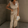 Full body view of female model wearing the Myla Cream Pink Floral Sleeveless Jumpsuit which features Cream Cotton Fabric, Pink Floral Print, Wide Leg Pants,  Tie Strap with Belt Loops, V-Neckline and Ruffle Straps