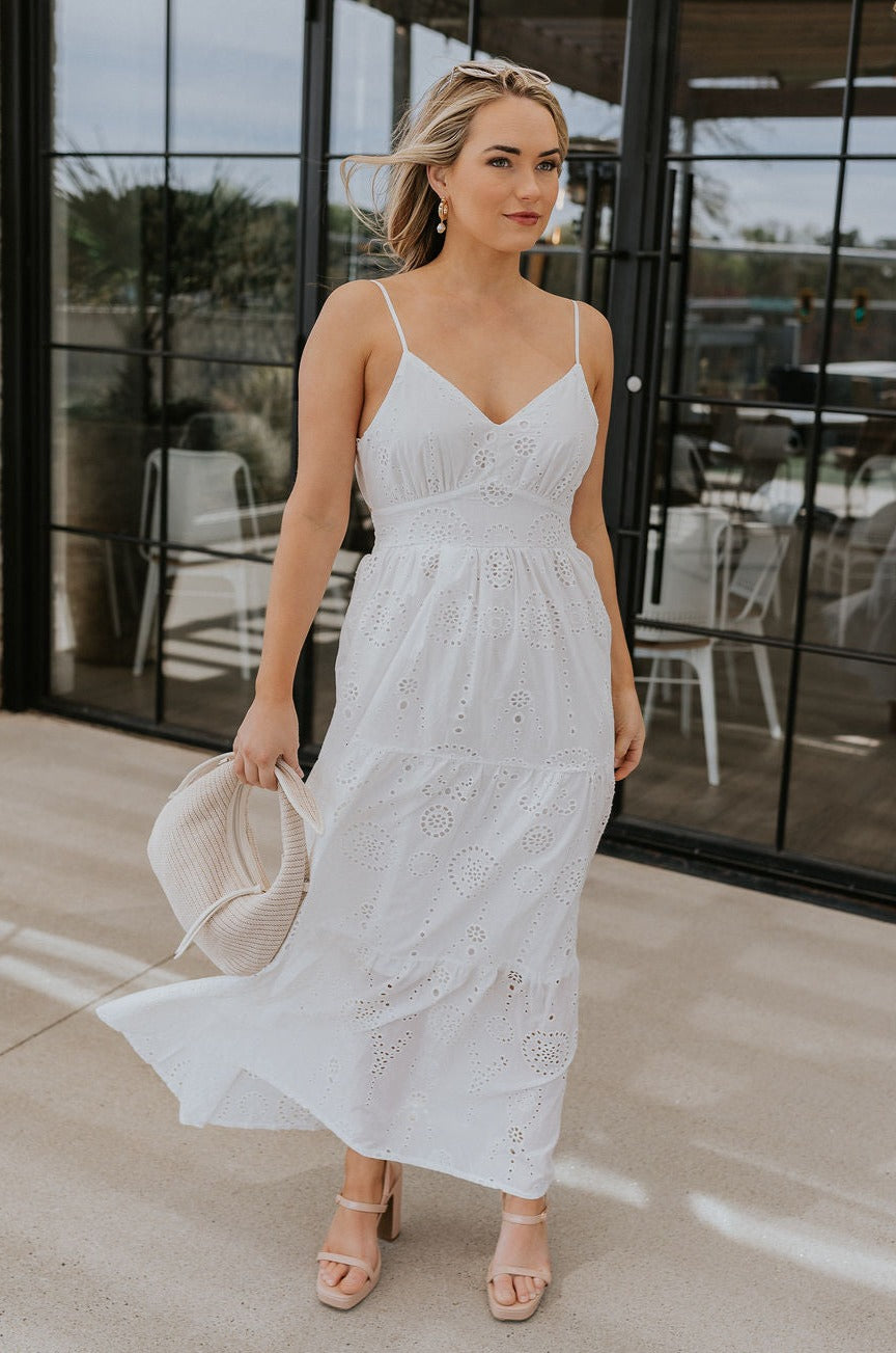 Full body view of female model wearing the Morgan Off White Eyelet Maxi Dress which features White Lightweight Fabric, Eyelet Pattern, White Lining, Maxi Length, Tiered Body, Sweetheart Neckline, Adjustable Straps and Open Back with Bow Tie 
