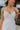 Close up view of female model wearing the Morgan Off White Eyelet Maxi Dress which features White Lightweight Fabric, Eyelet Pattern, White Lining, Maxi Length, Tiered Body, Sweetheart Neckline, Adjustable Straps and Open Back with Bow Tie