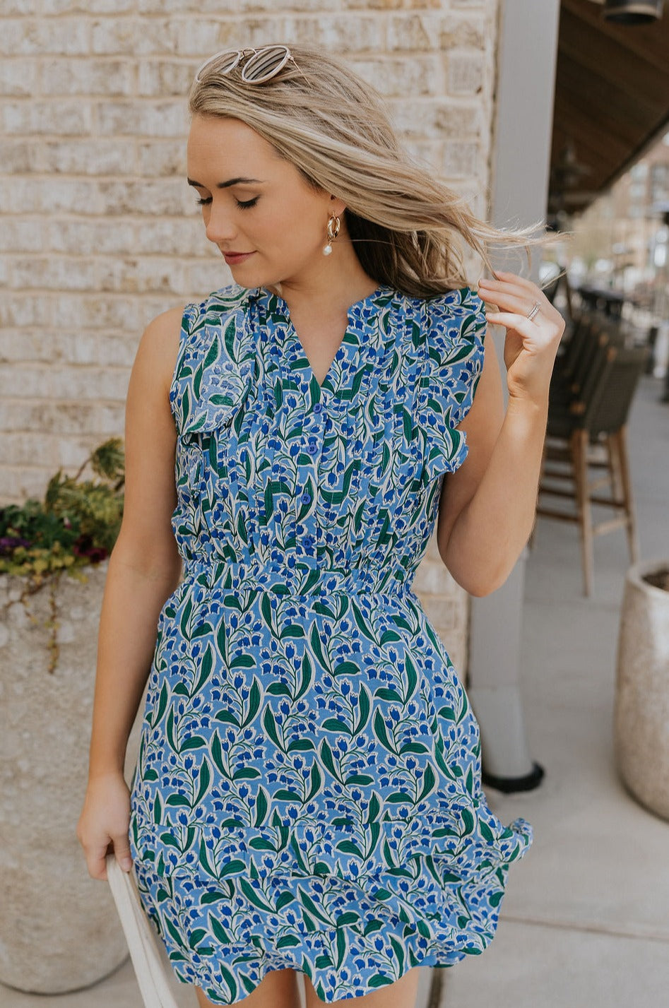 Front view of female model wearing the June Blue & Green Floral Ruffle Mini Dress which features Blue and Green Floral Print, Ruffle Tiered Design, Mini Length, High Neck with V-Cutout and Sleeveless