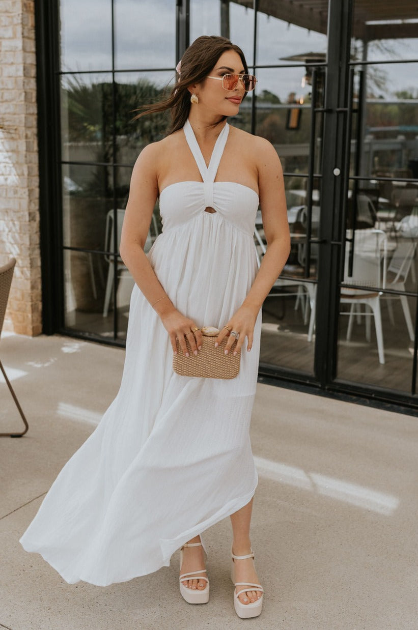 Full body view of female model wearing the Lina Off White Halter Neckline Maxi Dress which features White Lightweight Fabric, White Lining, Maxi Length, Slit Detail, Halter Tie Neckline with Key Hole Detail and Elastic Back