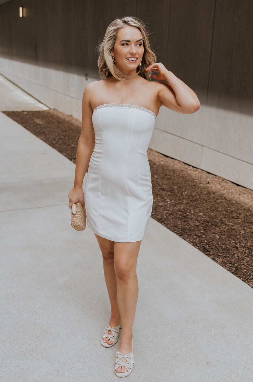 Full body view of female model wearing the Blaire Off White Rhinestone Strapless Mini Dress which features Lightweight White Fabric, Mini Length, White Lining, Strapless, Rhinestone Upper Hem Detail and Monochrome Back Zipper with Hook Closure