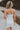 Back view of female model wearing the Blaire Off White Rhinestone Strapless Mini Dress which features Lightweight White Fabric, Mini Length, White Lining, Strapless, Rhinestone Upper Hem Detail and Monochrome Back Zipper with Hook Closure