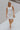 Full body view of female model wearing the Nadia Off White Halter Neckline Mini Dress which features White Textured Fabric, Mini Length, White Lining, Halter Neckline and  Monochrome Back Zipper with Hook Closure