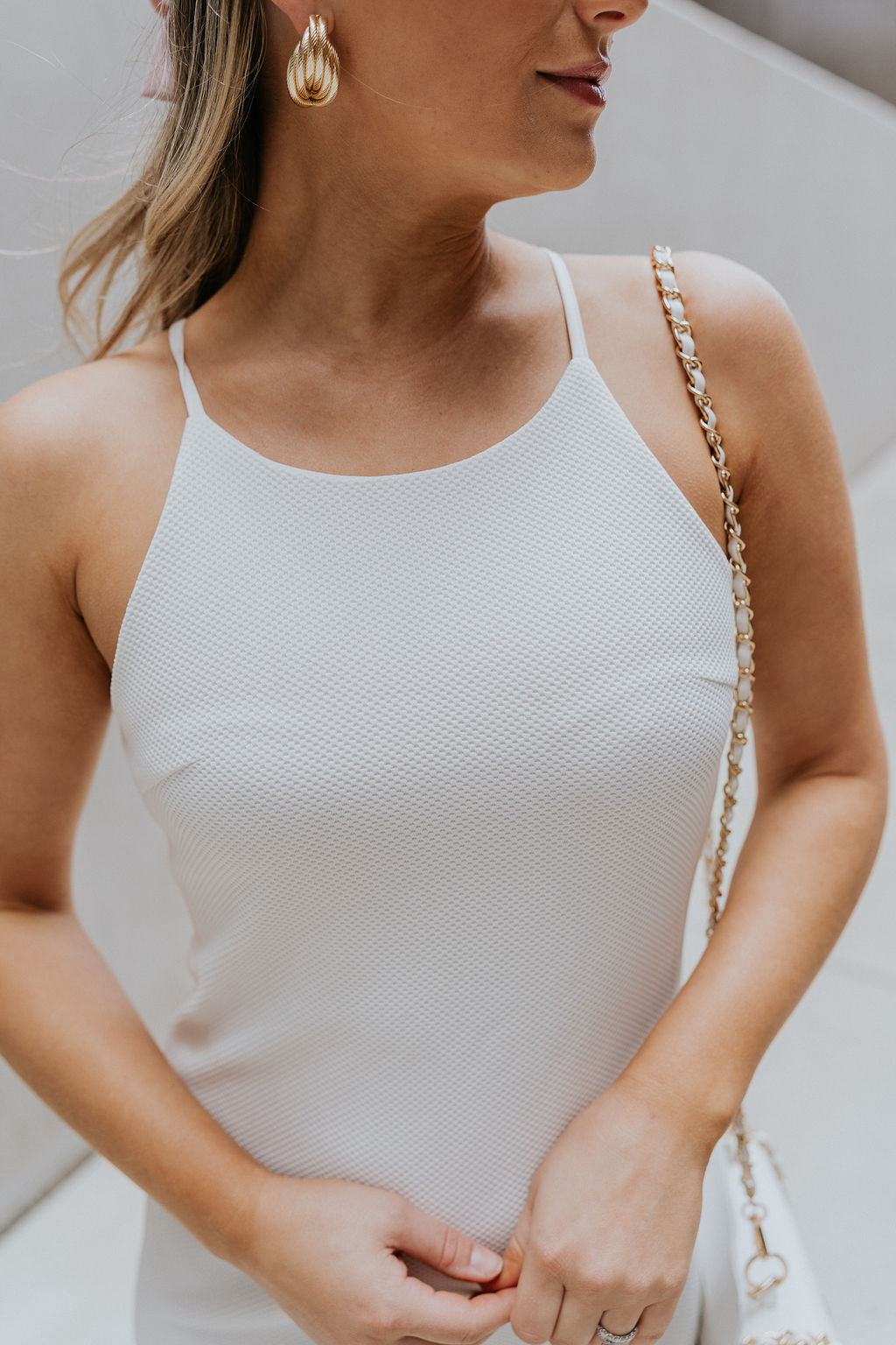 Close up view of female model wearing the Nadia Off White Halter Neckline Mini Dress which features White Textured Fabric, Mini Length, White Lining, Halter Neckline and Monochrome Back Zipper with Hook Closure