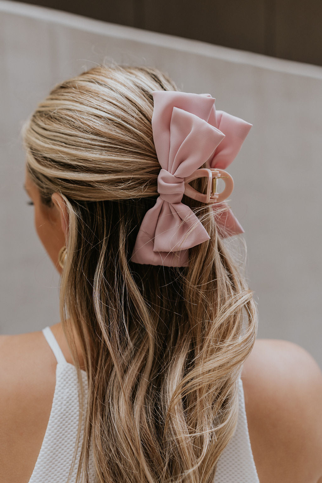 Back view of female model's hair; model is wearing the Laylani Hair Bow Claw Clip in Pink.