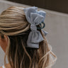 Back view of female model's hair; model is wearing the Laylani Hair Bow Claw Clip in Blue.